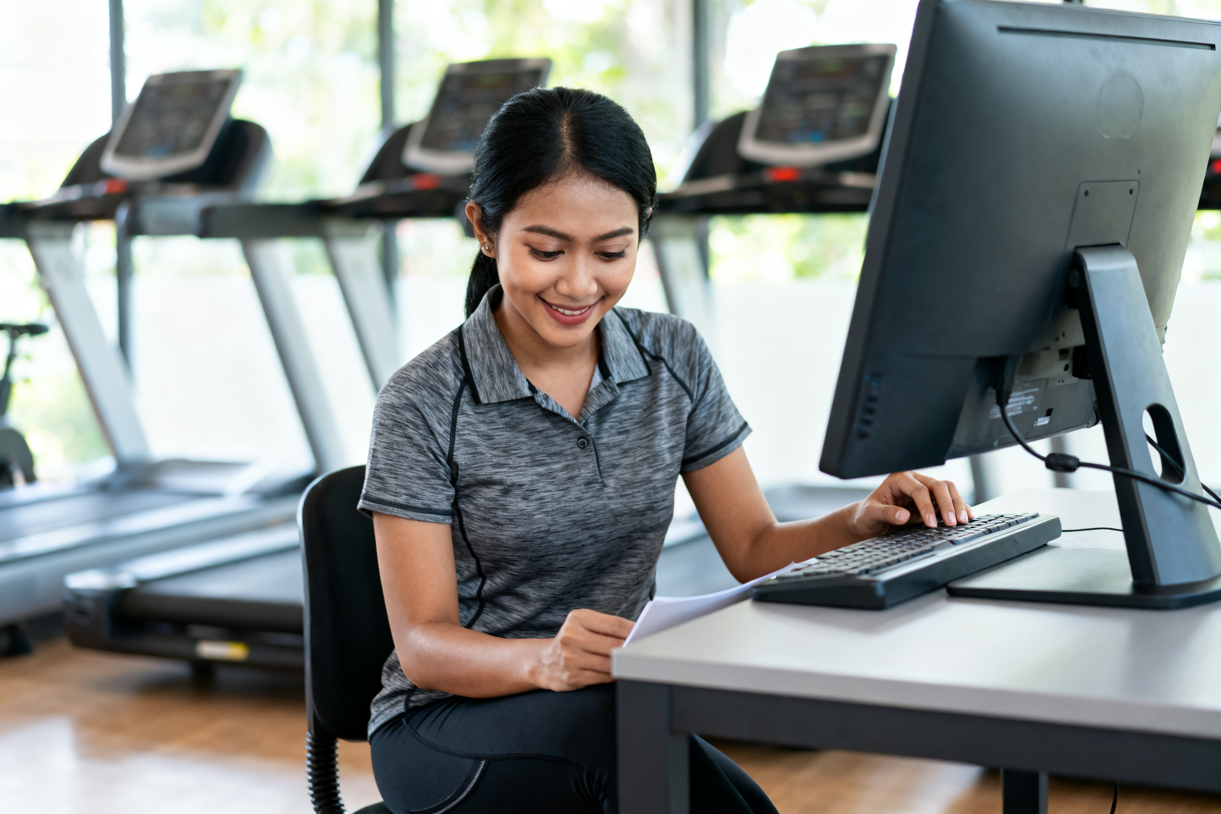 Indonesian woman examining treadmill controls while discussing exercise boosts overall health benefits
